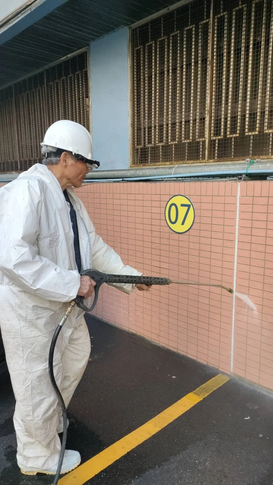 穿防護衣以高壓水槍沖洗磁磚牆面